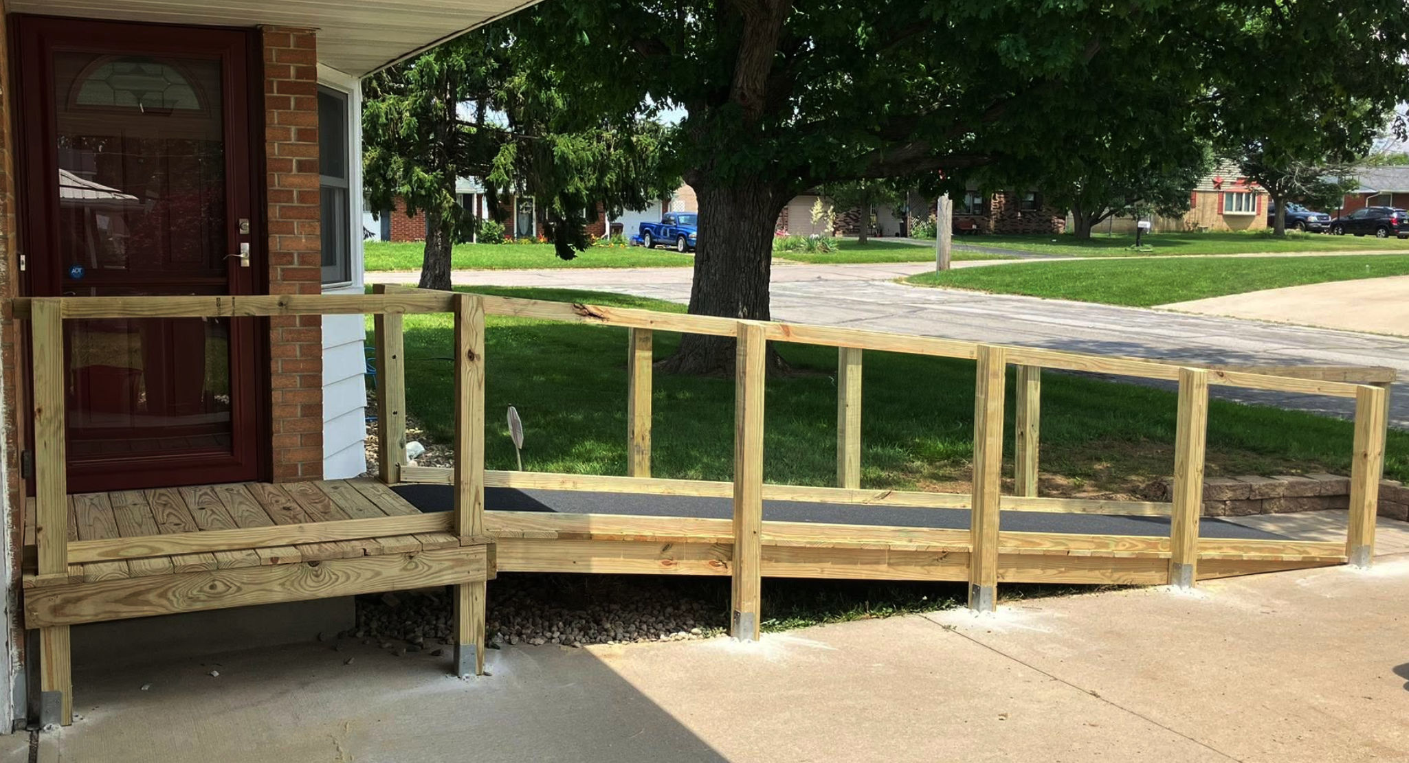 A pressure-treated lumber entry ramp with handrails leading to a front door.